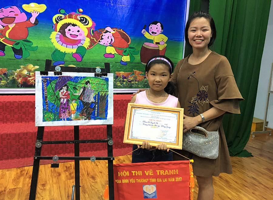 Cô bé Phạm Hồ Quỳnh Chi và cô giáo Mỹ thuật bên bức tranh đạt giải nhì Về thăm quê của mình. Ảnh: Phương Linh
